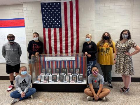 From left, Elijah Mayfield, Mandy Pendergrass, Kinleigh Queen, Americas LeQuire, Kaylin Ellis, Macie Postell and history teacher Nicole Hedden next to a memorial in honor of the 13 service members killed in Kabul last month. Students who helped with the exhibit but not pictured are Makayla Whitehead, Michael Samten, Madison Cogdill, Marlee Postell, Bronson Ludixen, Brianna Downs and O’Ryan Brockwell.