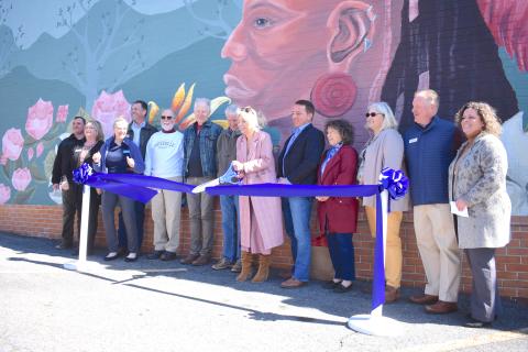 Artist Corrina Luckenbach, flanked by Eastern Band of Cherokee Indians Chief Richard Sneed and representatives from multiple organizations, cuts the ribbon on her work. The original mural was painted in 1992 by then Boy Scout Matthew Smith. Smith’s father Stephen was in attendance of the ribbon cutting which was held on Tuesday, April 19.