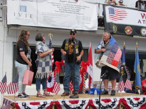 Photo by Linda Hagberg From left, VSO Danna Pash, Cherokee County Chamber Director Sherry Raines, Bruno Coltri and John Bandy are on stage as Raines is presented a Sisters Who Serve shawl and Bandy a Quilt of Valor.