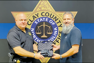 Investigator Todd Wingate conducts the traditional transfer of the firearm and badge worn by  Sheriff Bobby Deese.