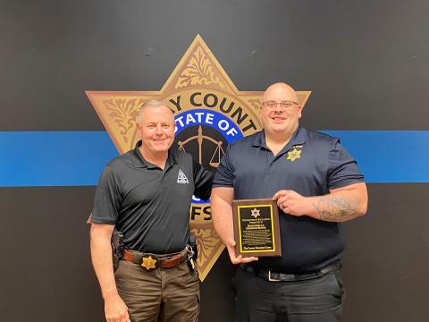 Sheriff Mark Buchanan presents Lieutenant Donovan Burke with a plaque of appreciation for his command of the detention center.