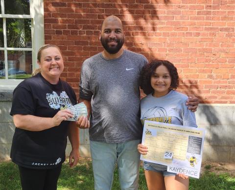 Coach Tammy Dills, left, presents the $500 cash winnings to Rick Jackson after choosing a date from Kaydence Morrow’s, board in the Hayesville volleyball program calendar raffle.