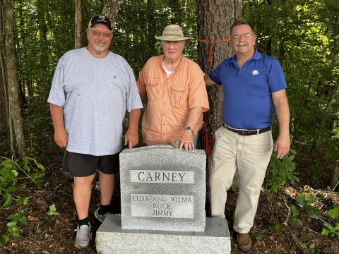 Deby Jo Ferguson • Clay County Progress Danny Jones, Ken Ball and Andy Gibson stand at the grave marker that distinguishes where the remains of the Carney family, Elda, Wilma, Buck and Jimmy are now buried together.
