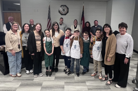 Angel Owens • Clay County Progress Staff and students of the Hayesville Elementary School Busy Beans Program, front, from left, Emily Hensley, Krysta English, Mily Ledford, Rejonie Gailley, Carly Anderson, Gabe Garcia, Bentley Smith, Gabe Canup, River Denton, Cayce Ledford and Kay Sprinkles, served drinks to the Clay County Board of Education, back, from left, Danny Jones, Robert Caldwell, Chairman Jason Shook, Superintendent Melissa Godfrey, Kelly Crawford and Josh Ashe Monday’s meeting.