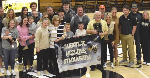 Gary Corsair • Clay County Progress Coach Darryl McClure holds helps hold the banner naming the gymnasium in his honor for a stellar career as girls’ high school basketball coach. He is surrounded by family members including his wife, Linda (helping hold the banner).