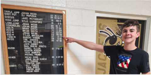 Eli Cheeks points to Tyler Breedlove’s record-setting time on display at the school. Cheeks has now set his own record in the 800 meter run.