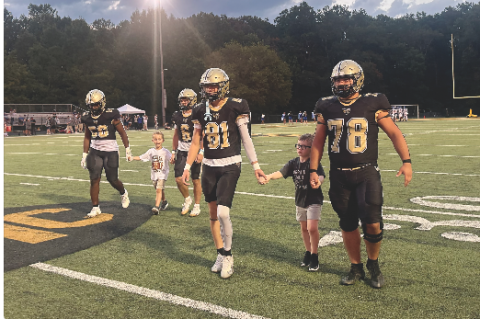 Gracie Taylor • Clay County Progress Varsity Jackets escort Rhet Lovingood and Cooper Godfrey onto the field Friday evening during Youth Night at Frank R. Long Memorial Stadium. From left are Will Brown, Lovingood, Tre Graves, Jameson Dawson, Godfrey and Rayland Martinez