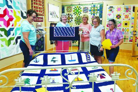Janelle Warren, Maureen Ripper, Cynthia Gonzalez, Gayle Cowdin and Joanna Marren put the finishing touches on the "Quilts!" exhibit at the Murphy Art Center downtown.