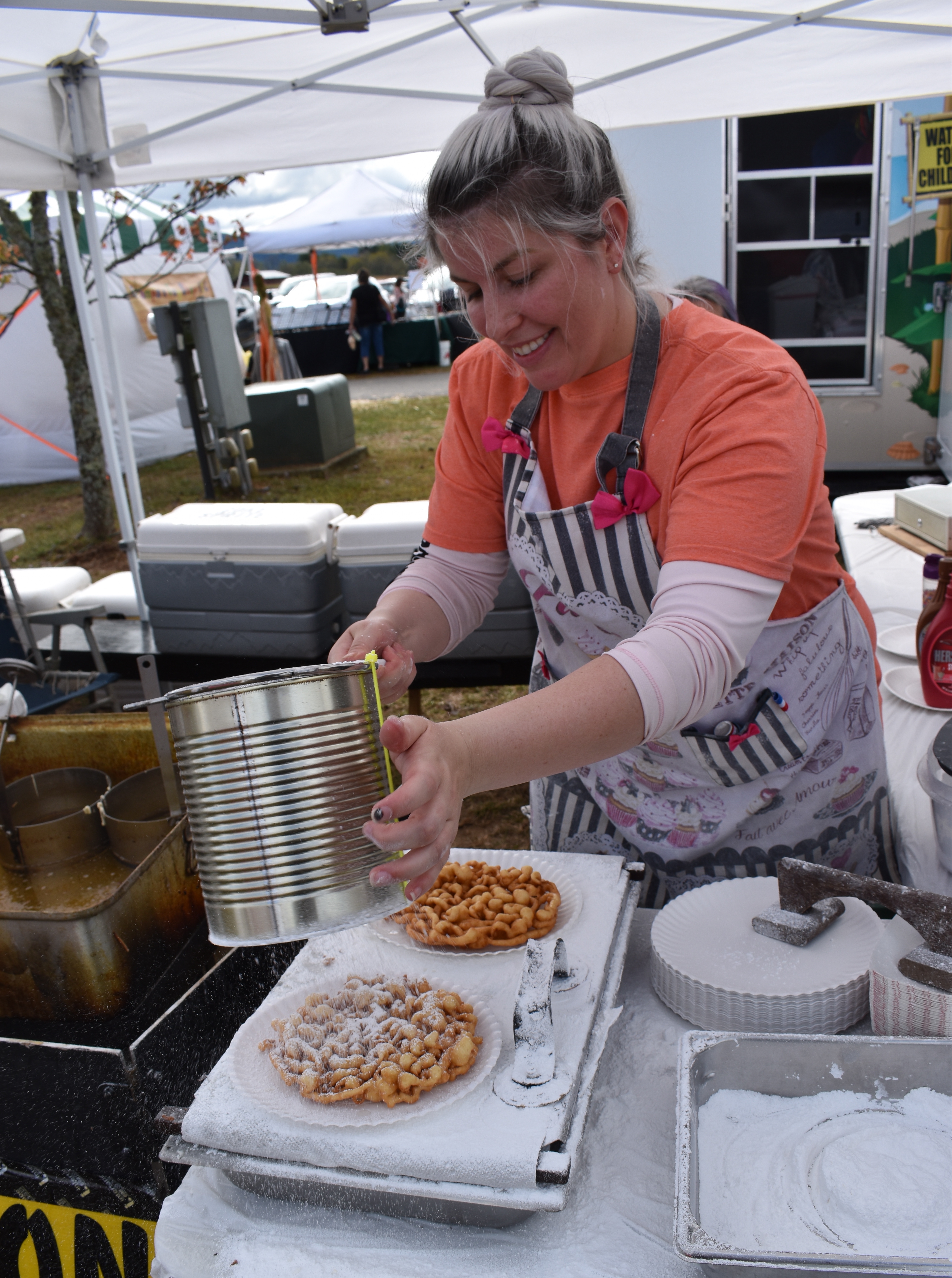 Laura Conrad prepares funnel cakes as visitors wait in line to taste the sweet treat.