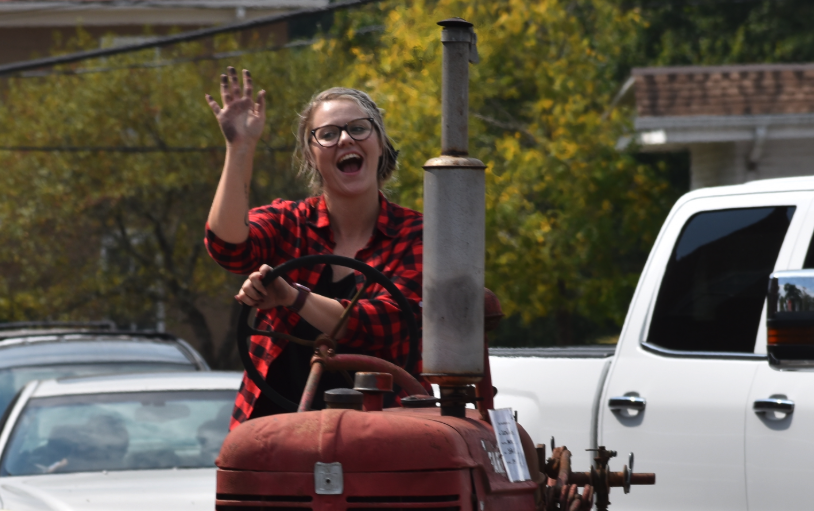 Becky Long • Clay County Progress // Ashley Ray Dawson waves to the crowds lining the streets of Hayesville and shows she’s not afraid to get a little grease under her nails as she enters town on a 1944 Farmall Super A owned by Justin Donaldson.