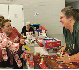 Lauren Tucker, left, shows Project Director Karen Coker baby sleepwear she is about to wrap during a gift wrapping event on Saturday, Dec. 10 at Catalyst Church in Hayesville. 