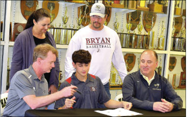 Gary Corsair • Clay County Progress Bryan College Head Basketball Coach Don Rekoske, left, and Hayesville Basketball Coach Mike Cottrell flank Yellow Jackets sharpshooter Ethan Hooper as Hooper commits to play at Bryan. Hooper's parents, Collette and Malcom are looking on.