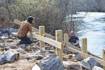 Jeremiah Smith of Big Deck Decking helps Nick Oliver of the Hinton Rural Life Center find the right angle for the kayak ramp they are building just below the bridge on Bulldog Drive in Murphy. Photo by Samantha Sinclair