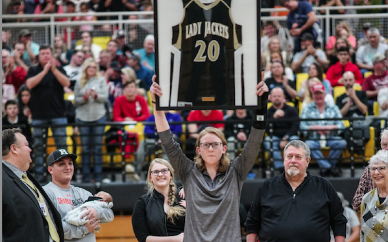 (Kelli Graves • Clay County Progress) Former Lady Yellow Jacket Amanda Thompson holds her now retired No. 20 high in front of a packed gym as her family looks on with smiles.