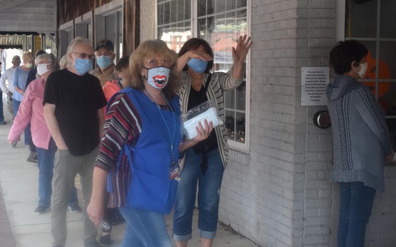 Clay County Election Board worker Linda Hagberg helps keep the line flowing during Thursday’s opening day of One-Stop voting in Hayesville. Lines of mostly masked voters stretched to the end of the sidewalk most of the day, at times inching around the corner of Church and Main.