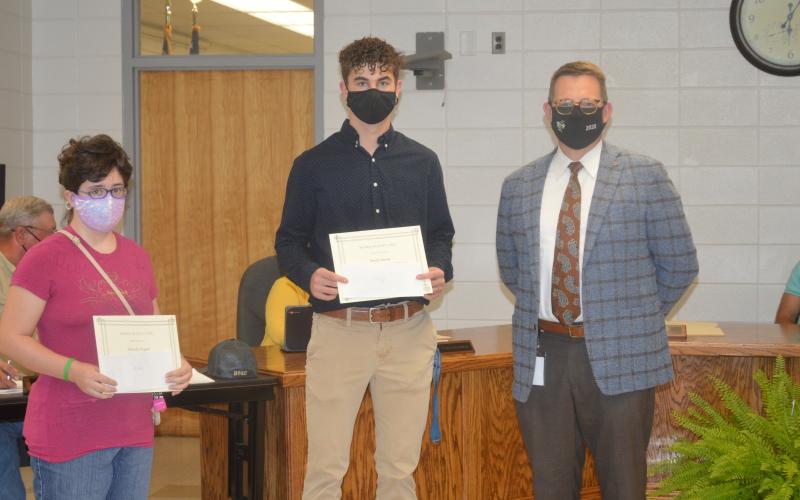 Hayesville High School students Michelle Pegues and Brady Shook tied for first place in the youth logo design contest held by People of Clay CARE. The students' logos were com- bined into one logo for the coalition. School Superintendent Dale Cole presented the students with their certificates and awards from the prevention coalition.