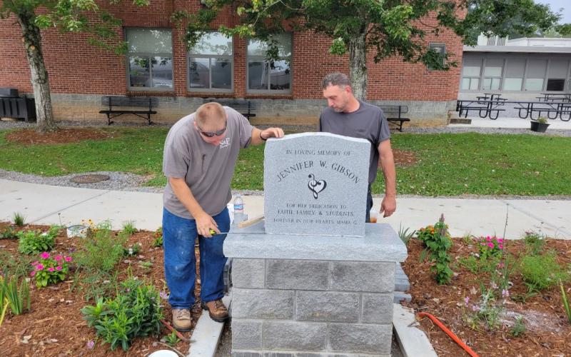 From left, Shannon Palmer from S and P Monument and Joey Buckner sets the stone.