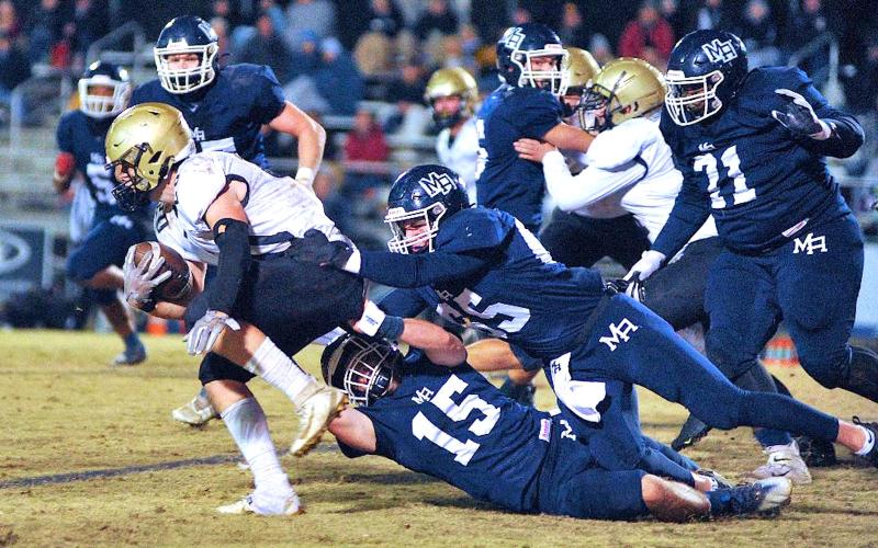 Zach Colburn • The Mount Airy News Yellow Jackets halfback Taylor McClure, No. 20, drags Mount Airy’s Landon Cox and Ian Gallimore.