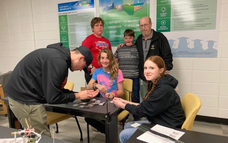 Hayesville Middle School members of the Fly Fishing Club watched as Jesse Shook, left, demonstrates fly making. Hawk Collins, center and Emily Lyvers on the right watch.  Standing, Ernie Taylor, Matthew Terry and Greg Charles, club leader.