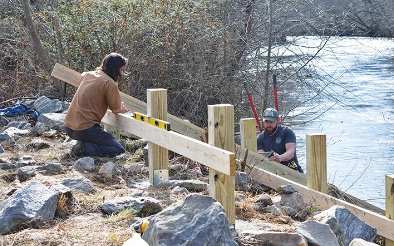 Jeremiah Smith of Big Deck Decking helps Nick Oliver of the Hinton Rural Life Center find the right angle for the kayak ramp they are building just below the bridge on Bulldog Drive in Murphy. Photo by Samantha Sinclair