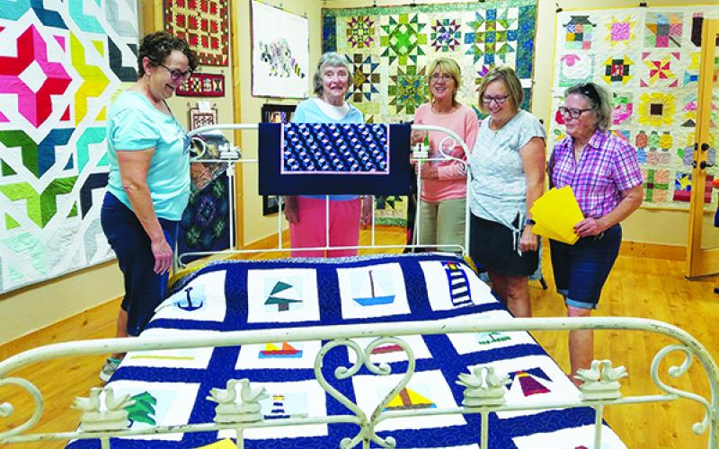 Janelle Warren, Maureen Ripper, Cynthia Gonzalez, Gayle Cowdin and Joanna Marren put the finishing touches on the "Quilts!" exhibit at the Murphy Art Center downtown.